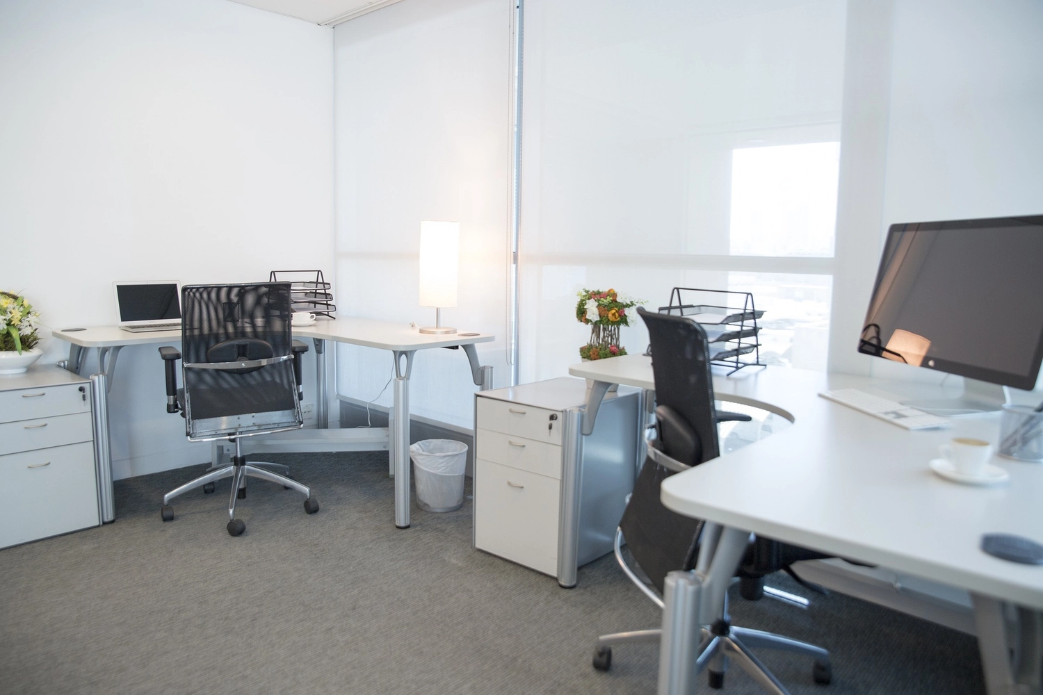 Splinta Clean GmbH – Gebäudereinigung – Diese möblierten Büroräume von IO Centers verfügen über weiße Schreibtische und ergonomische Netzstühle.